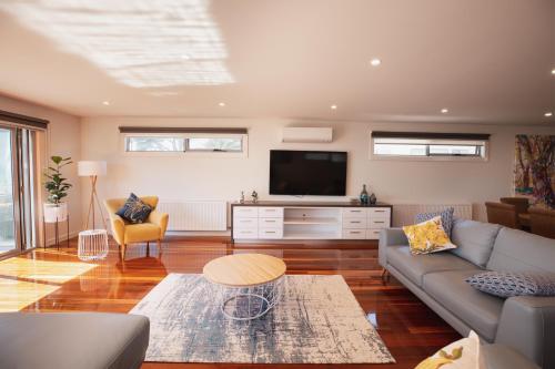 a living room with a couch and a tv at Luxurious 4 Bedroom House with Stunning Beach view in St Leonards in Saint Leonards