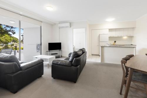 a living room with two couches and a kitchen at Ramada By Wyndham Marcoola Beach in Marcoola