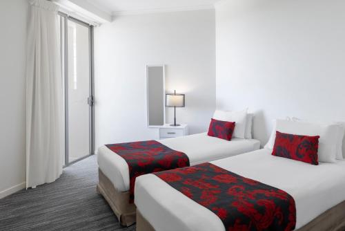 two beds in a hotel room with white walls at Ramada By Wyndham Marcoola Beach in Marcoola