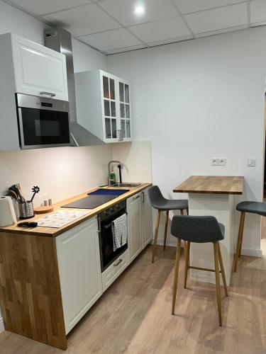kuchnia z białymi szafkami, stołem i krzesłami w obiekcie Studio Climatisé Centre Ville #9 w mieście Tulon