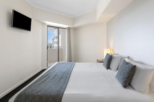 a bedroom with a large bed with a tv on the wall at Ramada By Wyndham Marcoola Beach in Marcoola