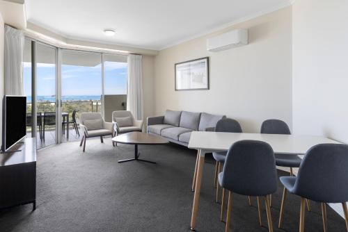 a living room with a couch and a table and chairs at Ramada By Wyndham Marcoola Beach in Marcoola