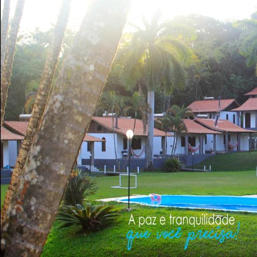a view of a pool and houses with palm trees at Pousada Tapera in Penedo