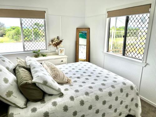 1 dormitorio con cama con almohadas y ventanas en The Luv Shack at the Beach en Yeppoon
