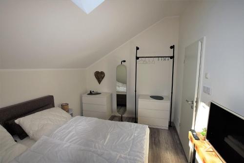 a white bedroom with a bed and a mirror at Meeresblick-Strandkieker-Haus-3-WE-45 in Hohwacht