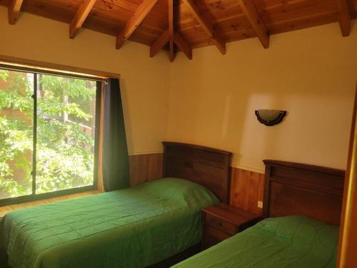 a bedroom with two green beds and a window at Townhouse Millatray in Caburgua