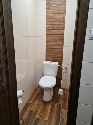 a small bathroom with a toilet and wooden floor at La Casa Rosa in Nová Baňa