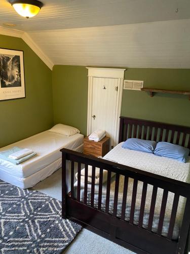 two beds in a bedroom with green walls at The Hostel California in Bishop