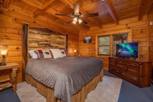 a bedroom with a bed and a flat screen tv at Voted #1 Cabin in Smokys! Spa, Arcade, Private, Creek, King Beds in Sevierville