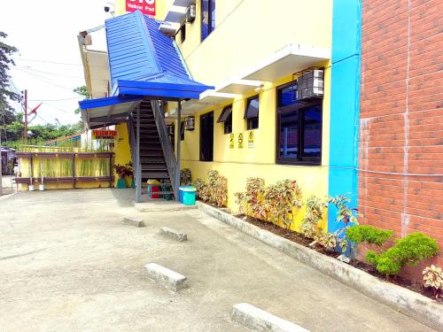a yellow building with a blue staircase in front of it at YellowPad Hotel (SM-Eco) in Davao City