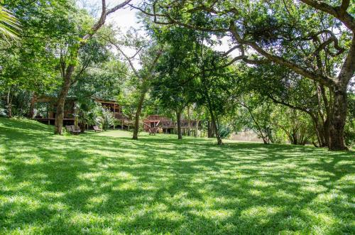 a field of grass with trees and a house in the background at Hippo Water Front Lodge in Nelspruit