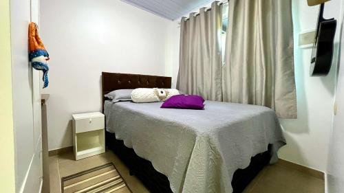 Un dormitorio con una cama con almohadas moradas. en Casa próx ao mar de Penha praia vermelha e Beto Carrero, en Penha