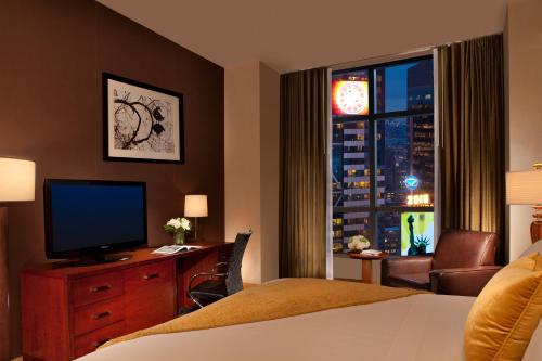 a hotel room with a bed and a desk with a television at Millennium Hotel Broadway Times Square in New York