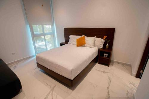 una camera da letto con un letto con un cuscino arancione sopra di Casa Moderna de 4 Pisos Con Rooftop Vista Al Mar a Isla Mujeres