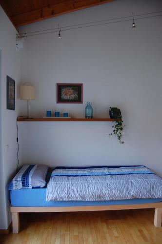 a bed in a room with a white wall at B&B Il Vigneto in Melano