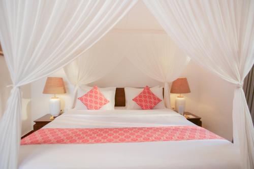a bedroom with a white bed with red pillows at Gayatri in Ubud