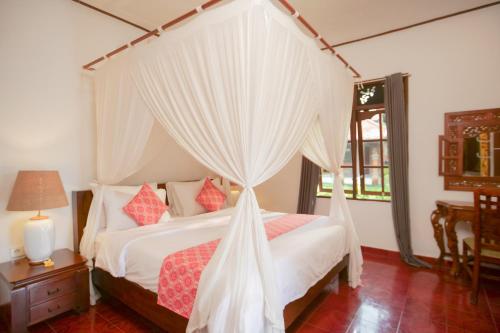 a bedroom with a canopy bed with white curtains at Gayatri in Ubud