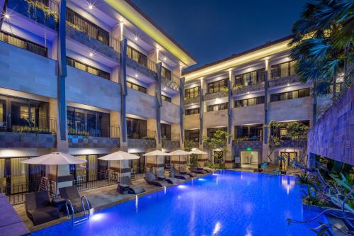 a hotel pool with chairs and umbrellas at night at Solia Legian Bali in Legian