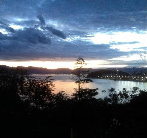 un tramonto su un lago con un albero nell'acqua di Por de sol no mar da cama a Caraguatatuba