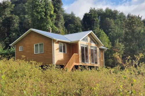 una pequeña casa de madera en medio de un campo en Cabaña El Estuario (Sector de Pocoihuen Alto), en Cochamó