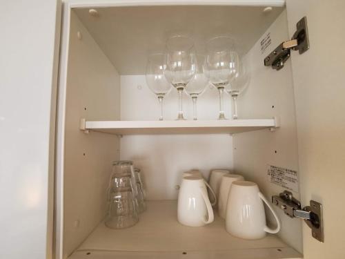 a cupboard with four wine glasses on a shelf at Fujio Pension Madarao Apartment Hotel & Restaurant in Iiyama