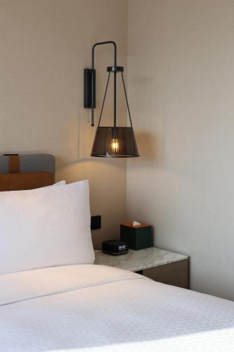 a bedroom with a white bed with a light above it at Four Points by Sheraton Shenzhen Bao'an in Shenzhen