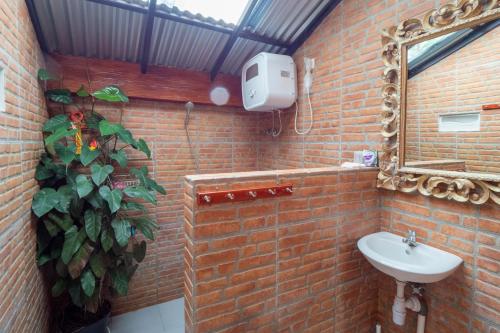 uma casa de banho em tijolo com um lavatório e um espelho. em rumah kayu sulawesi antique em Bedugul