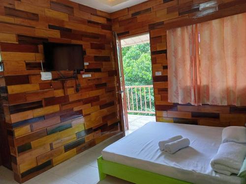 a bedroom with a wooden wall with a bed and a television at Woodland Inn in El Nido