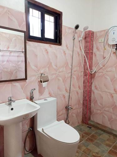a bathroom with a toilet and a sink and a shower at Woodland Inn in El Nido