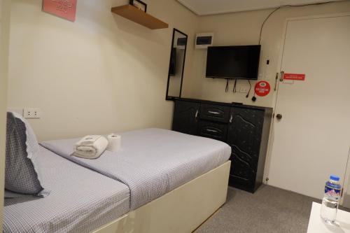a small bedroom with a bed and a flat screen tv at Sunset View Ridge Residences in Baguio