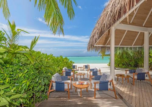 a patio with chairs and tables on a beach at Niyama Private Islands Maldives in Dhaalu Atoll