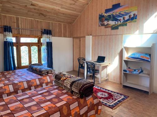 a bedroom with a bed and a desk with a laptop at Bloomfield Farmhouse and Eco-Resort in Darjeeling