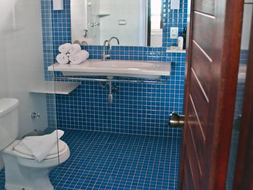 baño de azulejos azules con lavabo y aseo en Hotel & Pousada Tatajuba, en Canoa Quebrada