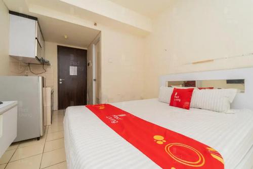a bedroom with a large bed with a red blanket on it at RedLiving Apartemen Serpong Green View - Farida Property in Ciater-hilir