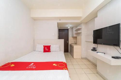 a hotel room with a bed and a flat screen tv at RedLiving Apartemen Serpong Green View - Farida Property in Ciater-hilir