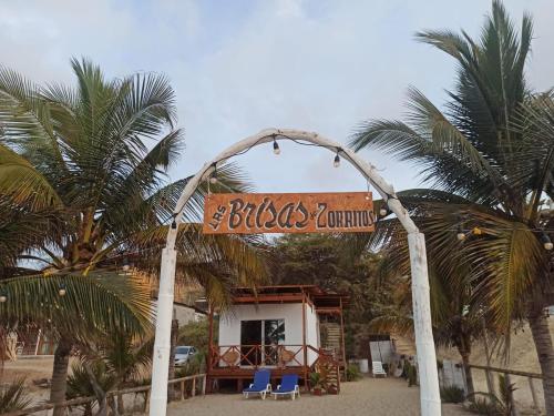 a sign for a hotel on a beach with palm trees at Hospedaje "Las Brisas de Zorritos" in Zorritos