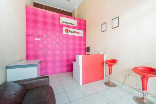 a living room with a couch and a pink wall at RedLiving Apartemen Serpong Green View - Farida Property in Ciater-hilir