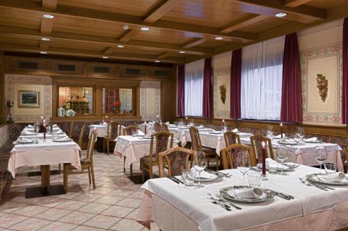 a dining room with tables and chairs with white tablecloths at Hotel La Serenella in Moena