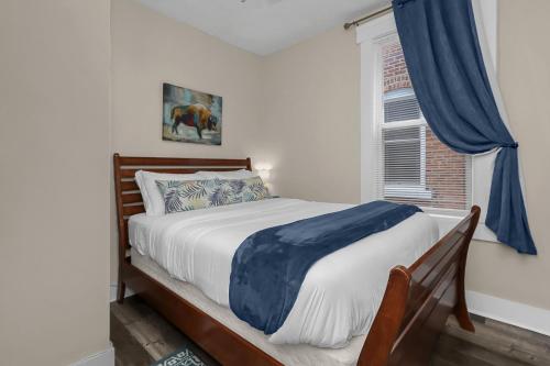 a bedroom with a bed with blue curtains and a window at Modern 2BR near DT, 8min walk to Park&Conservatory in Columbus