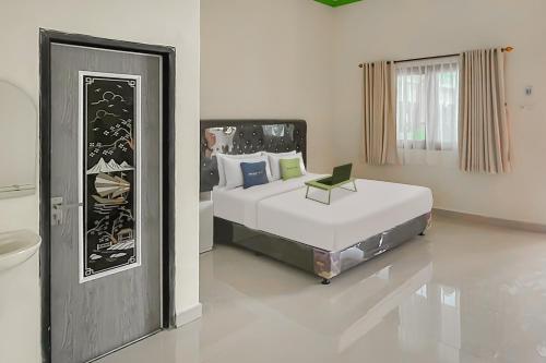 a bedroom with a bed and a chair in it at Urbanview Hotel Tirtamaya Jaya Indah Indramayu by RedDoorz in Indramayu