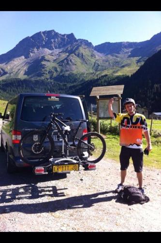 a man standing next to a car with a bike on the back at Mortirolo in Mazzo di Valtellina