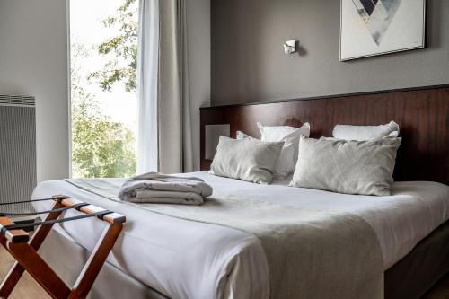 a bedroom with a bed with white sheets and a window at Domaine de Cicé-Blossac, Resort Spa & Golf in Bruz
