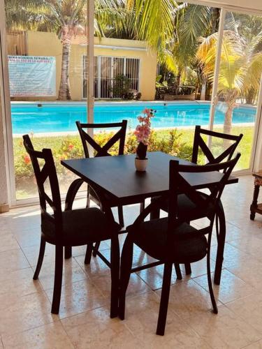 a table and chairs with a vase of flowers on it at CASA HUELLAS EN LA ARENA in Ixtapa