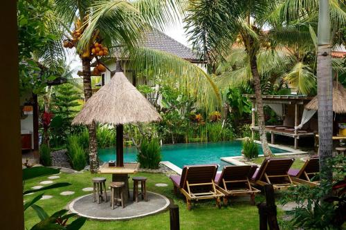 a resort with a pool and chairs and a table at Arimba at Bisma in Ubud