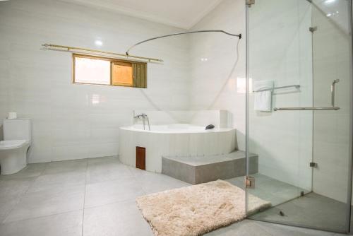 a bathroom with a shower and a tub and a sink at The Winford Boutique Hotel Airport in Accra