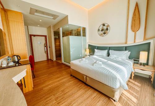 a bedroom with a large bed with a glass wall at Grand Lord Hotel & Residence - Khao chi chan Pattaya in Na Jomtien