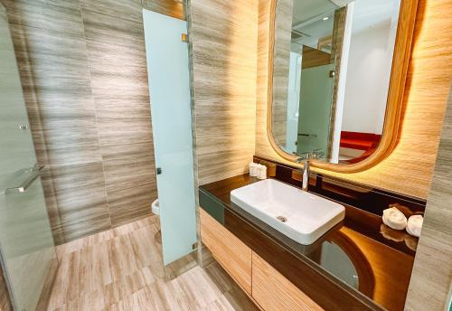 a bathroom with a sink and a mirror at Grand Lord Hotel & Residence - Khao chi chan Pattaya in Na Jomtien