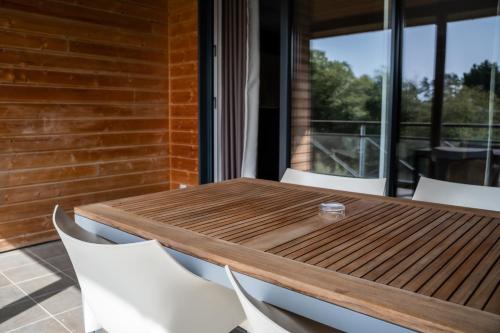 a wooden table and white chairs on a patio at Domaine de Cicé-Blossac, Resort Spa & Golf in Bruz