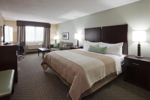 a hotel room with a large bed and a chair at GrandStay Hotel & Suites - Glenwood in Glenwood