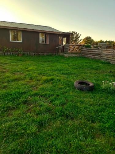 a yard with a house and a tire in the grass at Cabañas Josabi in Concepción